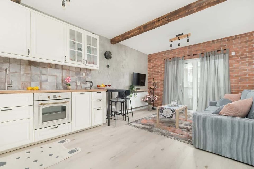 An airy kitchen and dining space with white cabinets and wooden ceiling beams.

