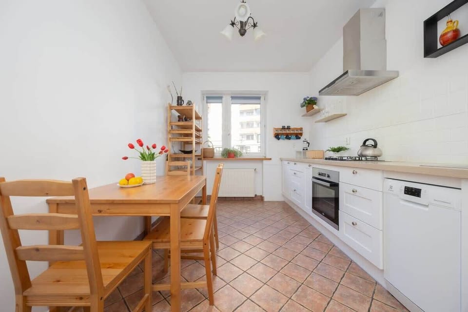 A kitchen featuring a wooden dining set, flower arrangements on the table, and a homey vibe with warm lighting.