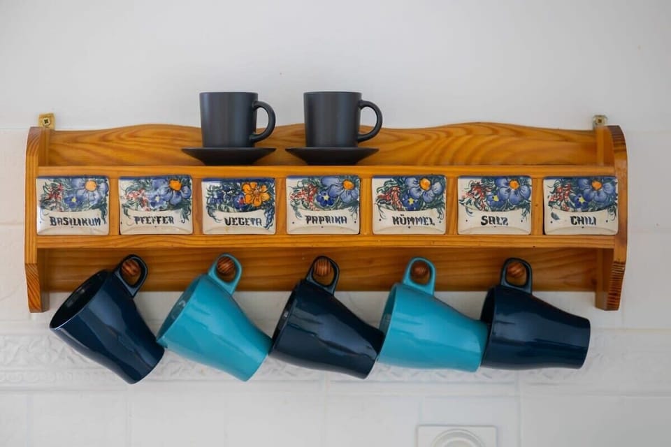 A charming display of mugs in a wooden shelf, each with a unique design. The neatly organized collection adds a personalized, homely touch to the kitchen space, making it feel welcoming and lived-in.