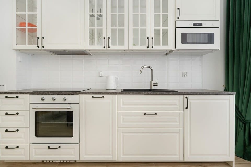 A functional kitchenette with white cabinets and modern appliances is perfect for preparing simple meals.