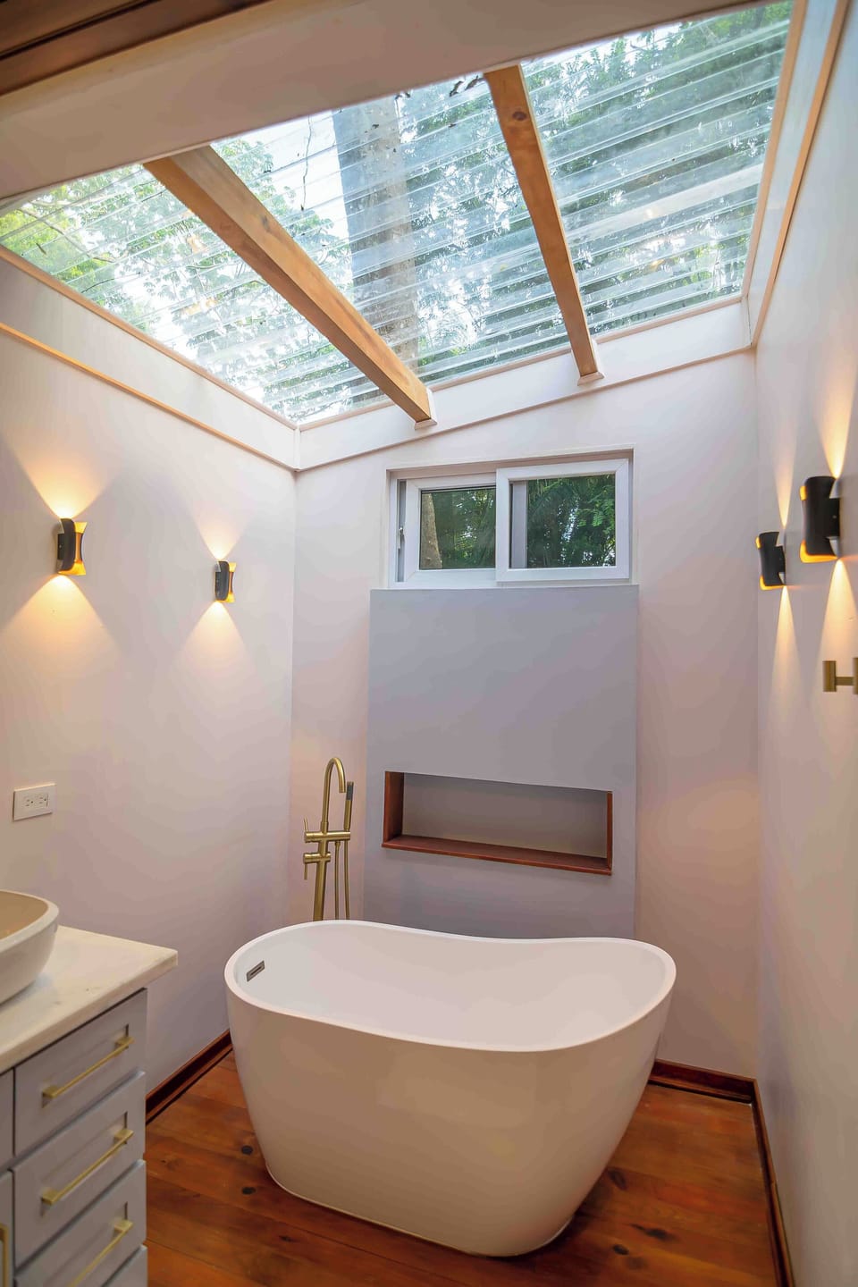 This elegant space has a freestanding bathtub and a bright natural skylight.