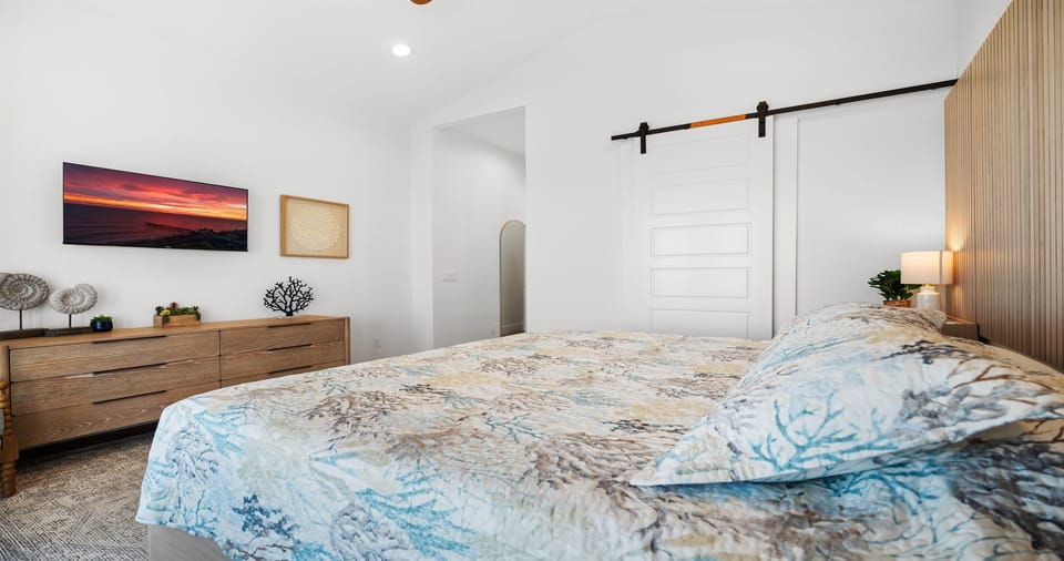 A serene coastal retreat featuring a plush bed, warm wood accents, and a modern barn door—clean lines, soft textures, and a calm, airy feel designed for deep rest and slow mornings.