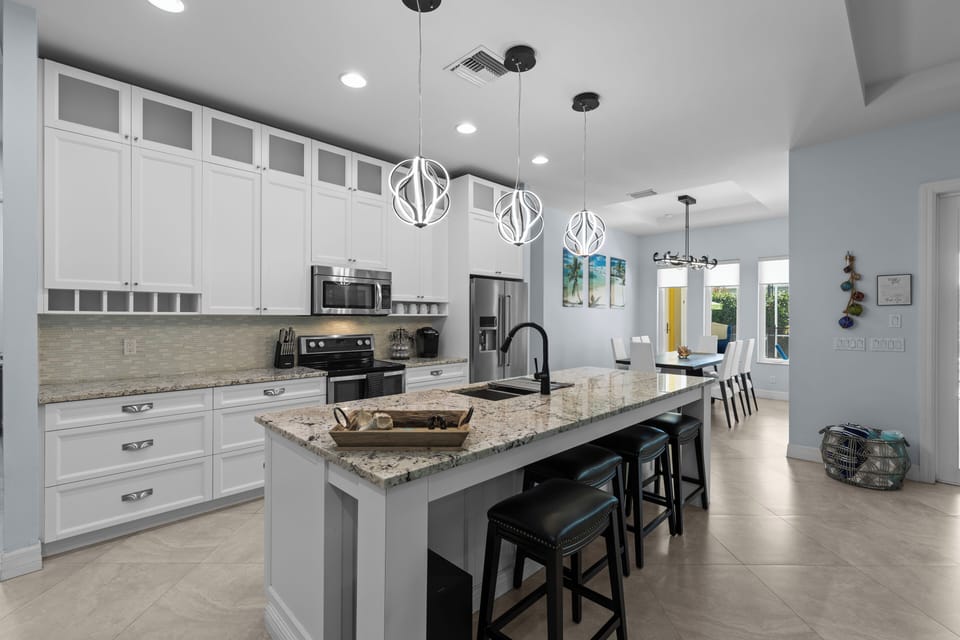 A fully equipped kitchen has granite countertops, an eat-in bar, and stainless steel appliances.