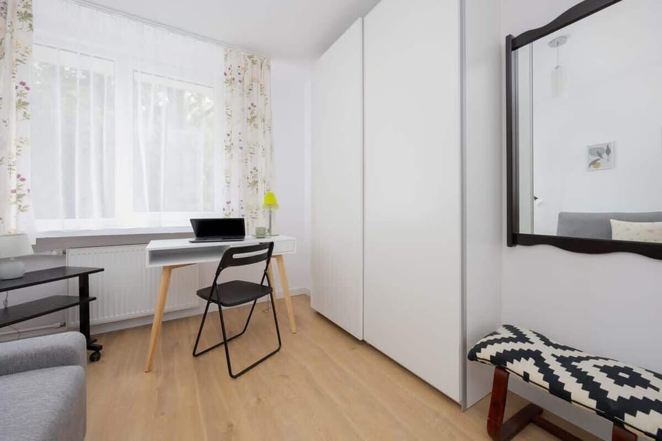 A room with a long desk setup, grey chair, and wardrobe for practical use.

