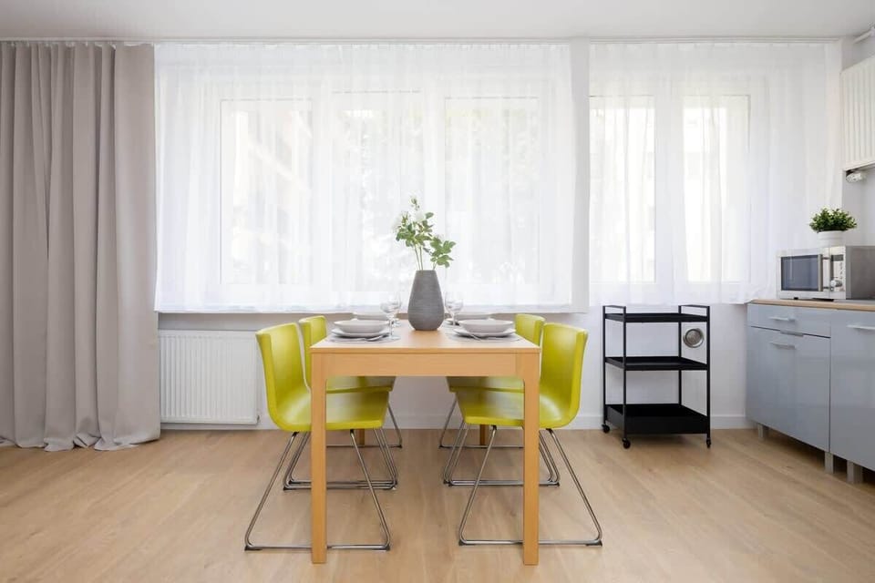 A dining nook with large windows, a simple wooden table, and modern décor.

