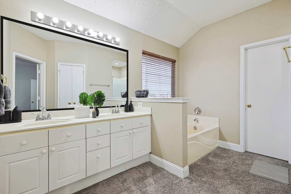 Enjoy some quiet “me time” in this ensuite bathroom! With dual vanities, an oversized glass mirror, and a private Jacuzzi, it’s time for some rest and relaxation.