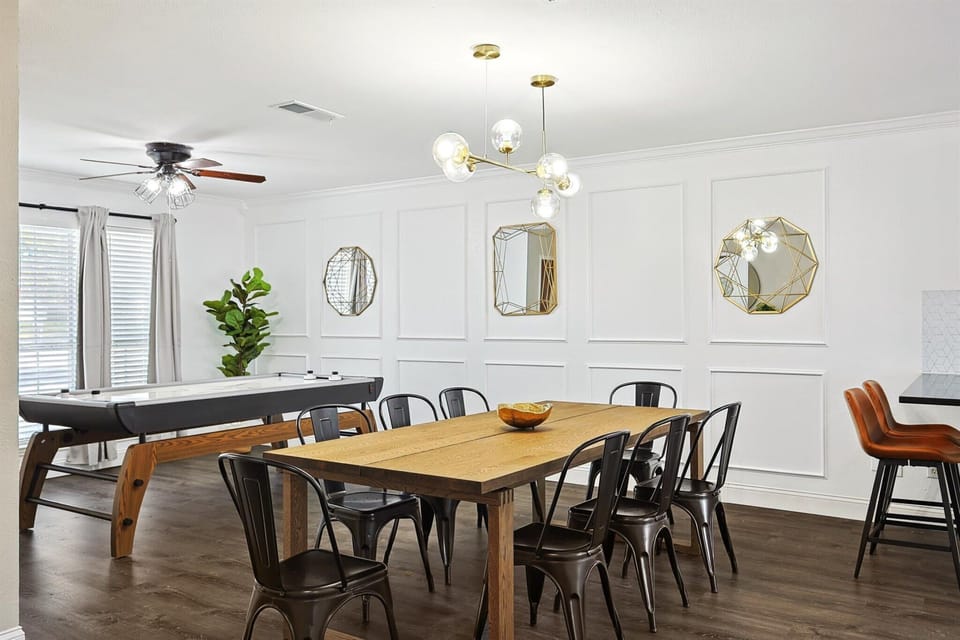 Equipped with a stylish light fixture, beautiful Wainscotting walls, and decorative geometric mirrors, this spacious dining area offers seating for eight. 