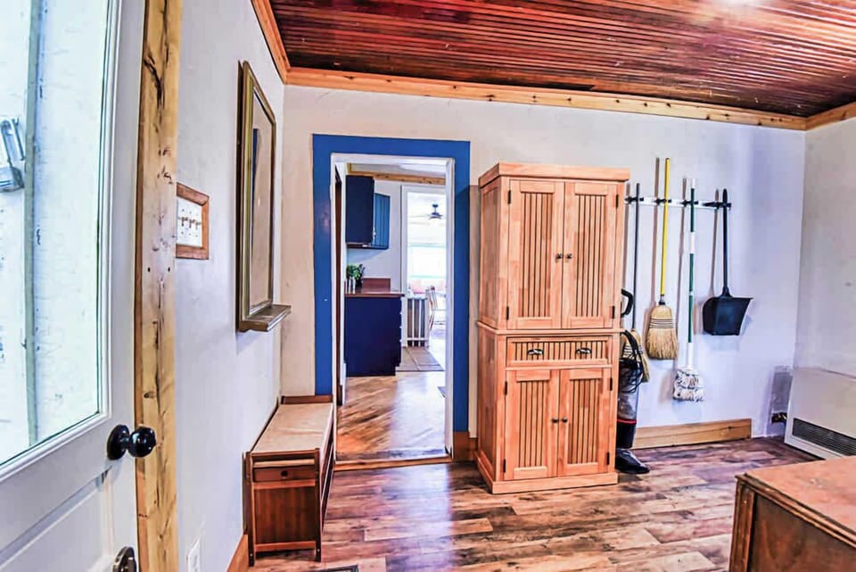 A rustic hallway with a cabinet, hardwood floors, and a wood ceiling.