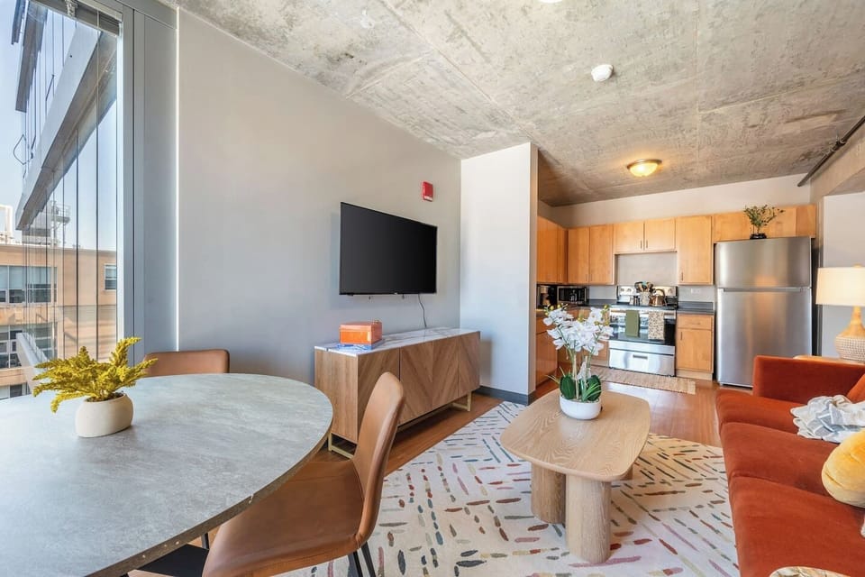 Bright and modern open-concept living space with a fully equipped kitchen, cozy seating, and city views.