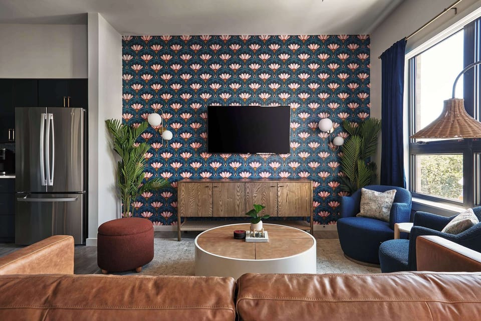 A stylish, modern living space with a vibrant, patterned accent wall, cozy seating, and sleek furniture, blending contemporary design with warm, inviting textures.