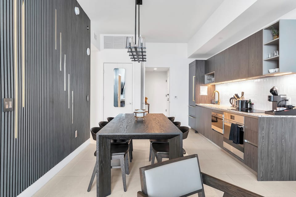 The table is positioned by the accent wall, enhanced with built-in lighting.