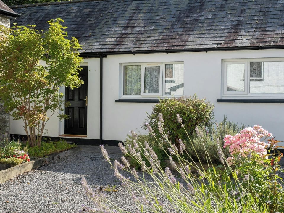 Outside of cottage with gravel path and raised flower beds