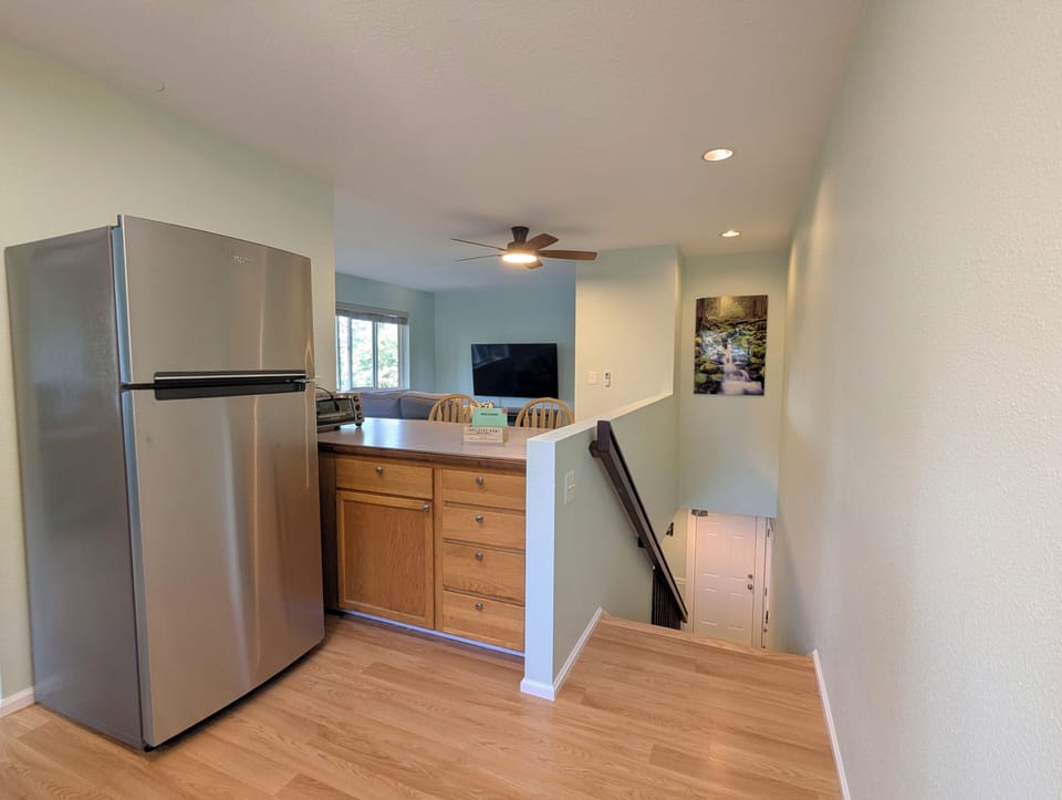 Upstairs kitchen island, refrigerator and living room.