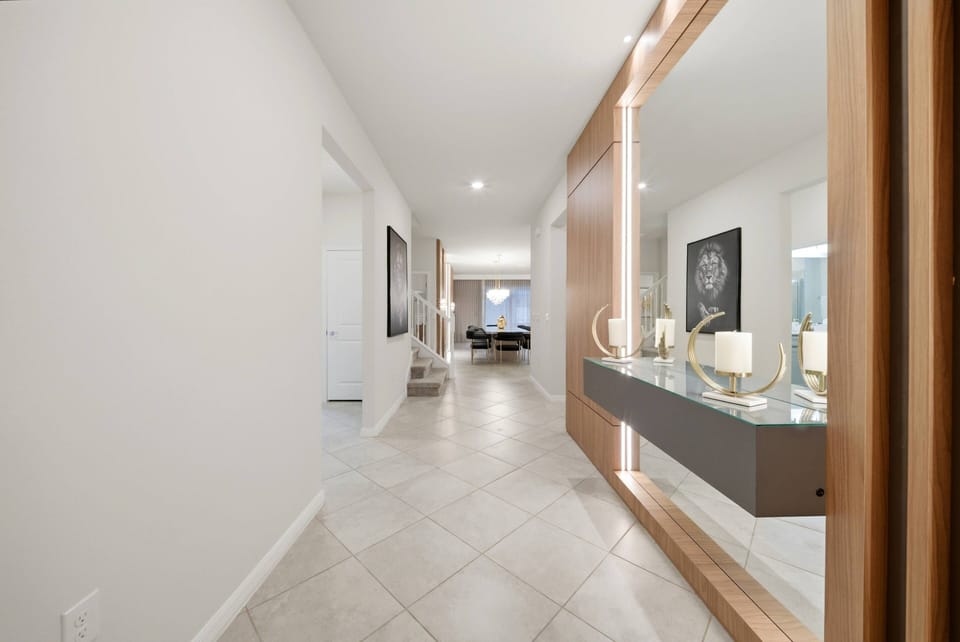 Step into a well-lit hallway featuring sleek tile floors and a stunning wooden console table, perfect for your personal touches. The subtle artwork adds character while guiding you towards the inviting living area ahead.