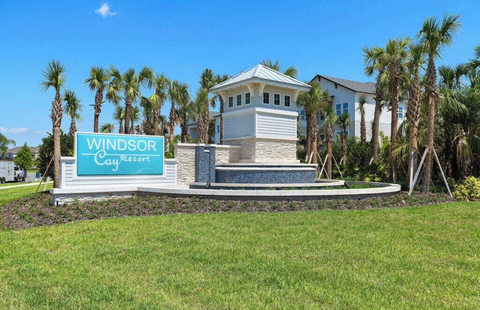 Welcome to a charming coastal escape marked by a bright blue sign and lush palm trees. The crisp white architecture invites you to discover the comforting features that await inside. Enjoy your stay!