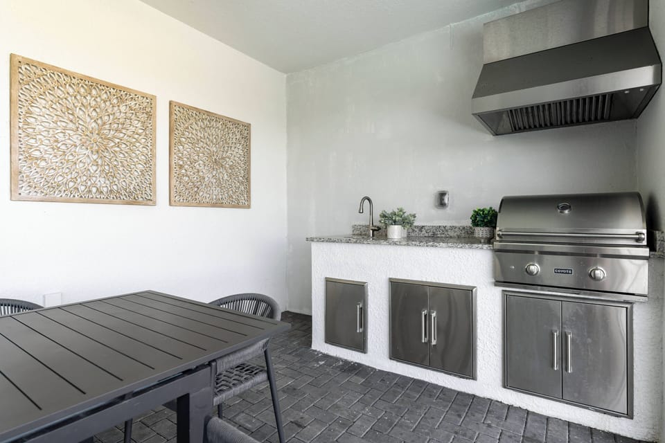 This modern kitchen boasts sleek stainless steel appliances and a stylish granite countertop, ideal for meal prep. The understated decor and textured wall art enhance the clean cabinetry, fostering a warm and inviting atmosphere.