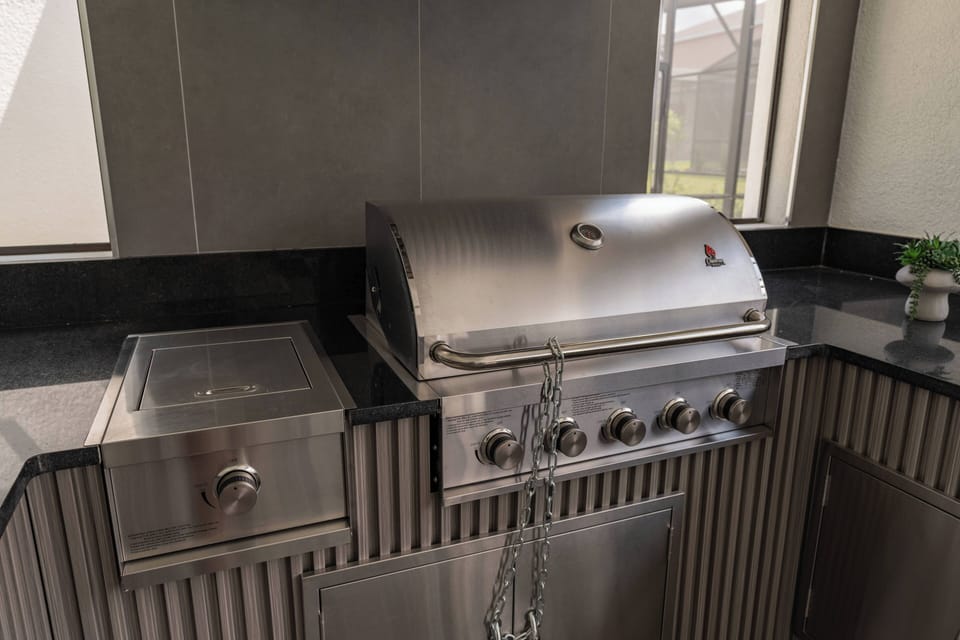 Elevate your culinary experience with this sleek outdoor grill, featuring polished stainless steel and a spacious countertop. Surrounded by large windows, enjoy a seamless connection to the outdoors while preparing meals in style.