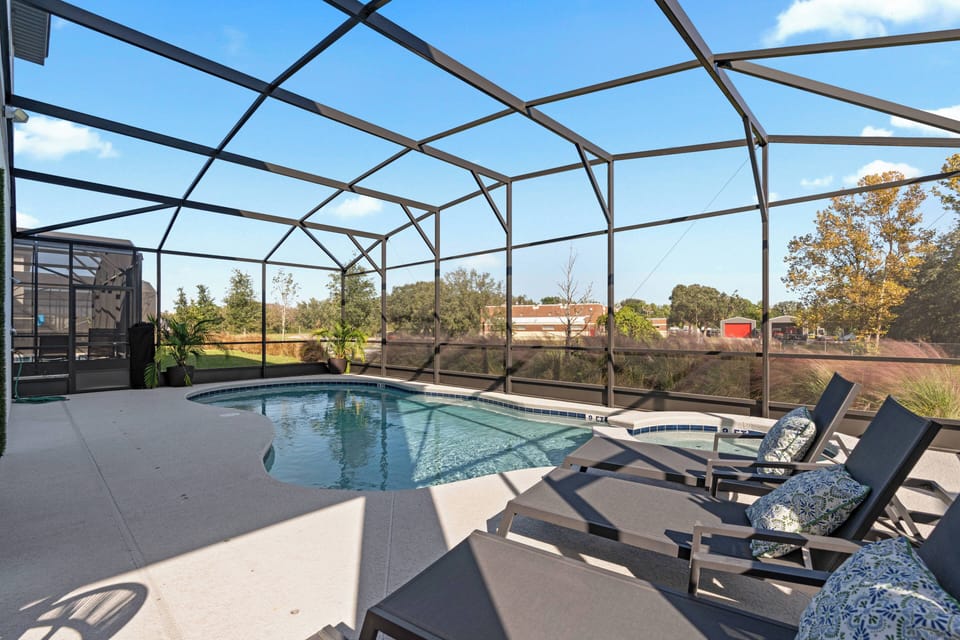Step outside to your private pool area, where comfortable lounge chairs await you to unwind under the sun. Enjoy the refreshing screened enclosure while taking in the serene surroundings and beautiful blue skies.