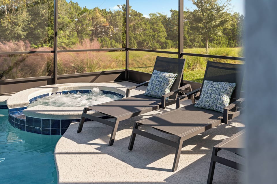 Unwind in this outdoor oasis featuring a sparkling hot tub and sleek lounge chairs, perfect for soaking up the sun. The scenic backdrop of lush greenery enhances the tranquil atmosphere, inviting relaxation at every turn.