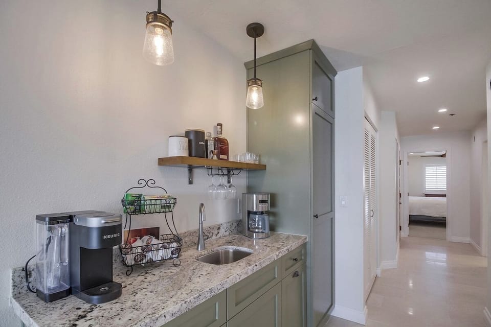 Dry bar across from the kitchen includes additional cookware and storage in the cabinets.