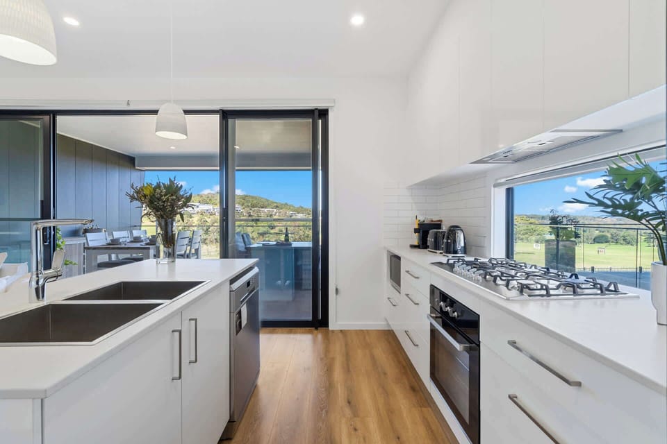 Step into this bright kitchen, featuring sleek white paint and modern appliances—oven, dishwasher, and fridge—perfect for effortless cooking and entertaining