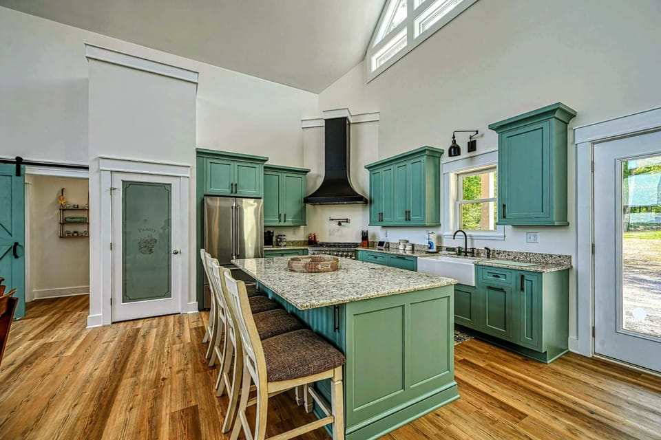 Spacious and modern kitchen with a large island, stylish green cabinetry, and plenty of natural light, perfect for cooking and entertaining
