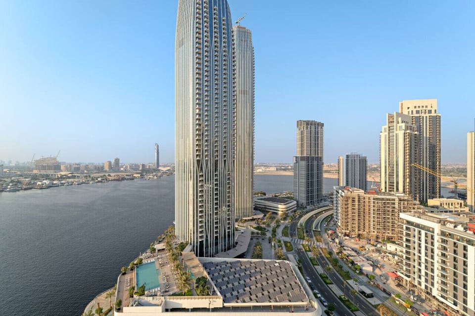 Daytime view of modern skyscrapers next to a body of water and a city.
