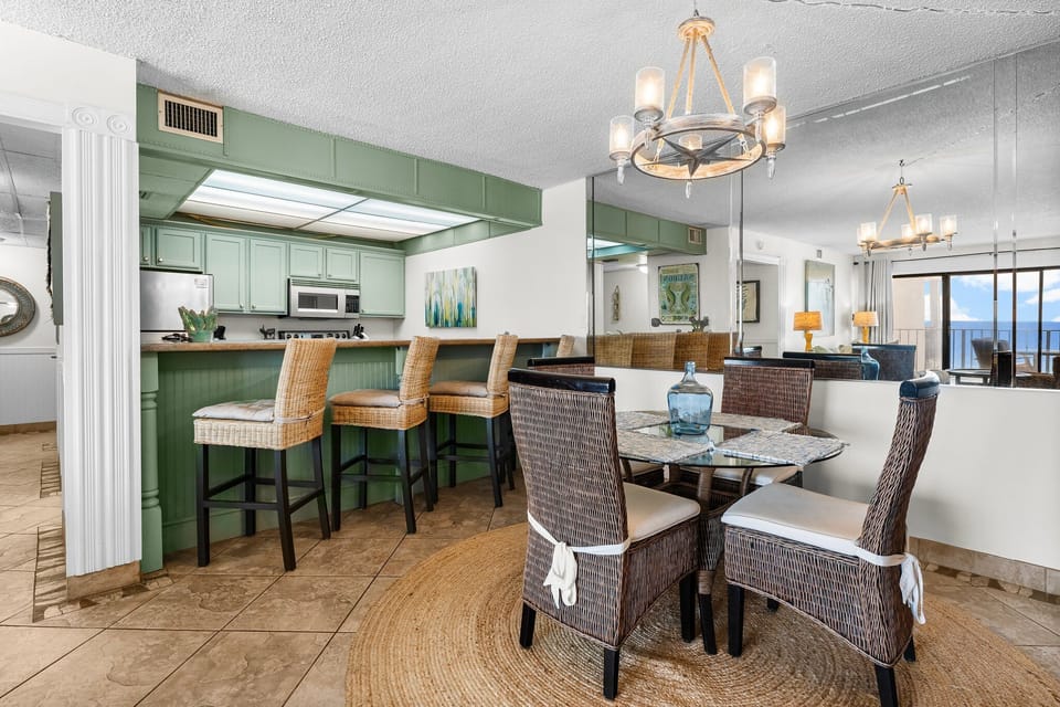 Open dining area with wicker chairs and a green kitchen bar for casual meals.