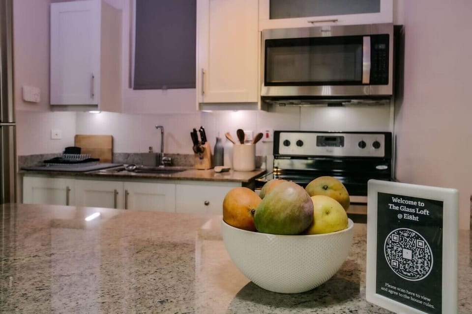 Kitchen counter w/ fruit bowl, microwave, stove & cooking space