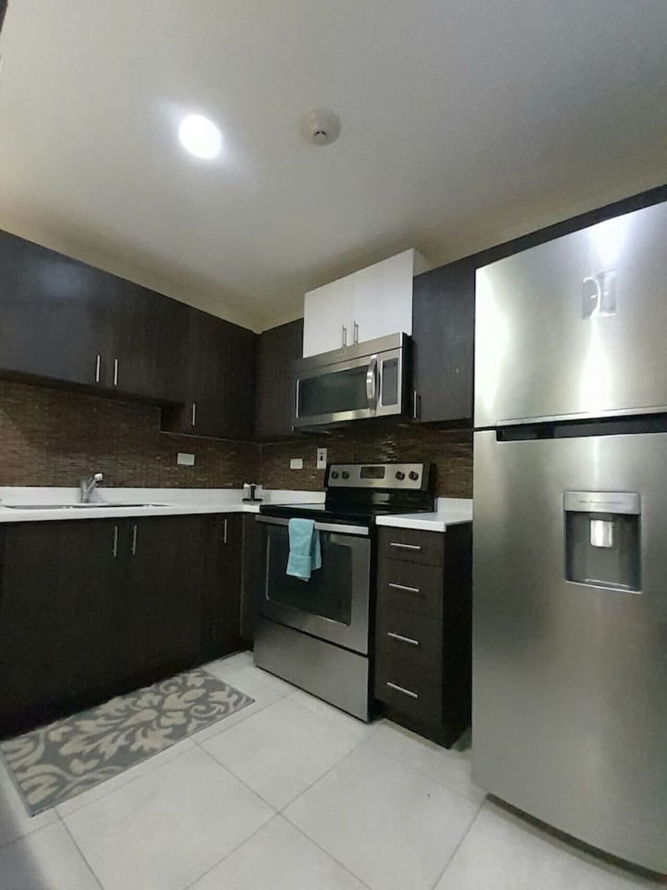 Modern kitchen w/ dark cabinets, full-size fridge & sleek cooking space