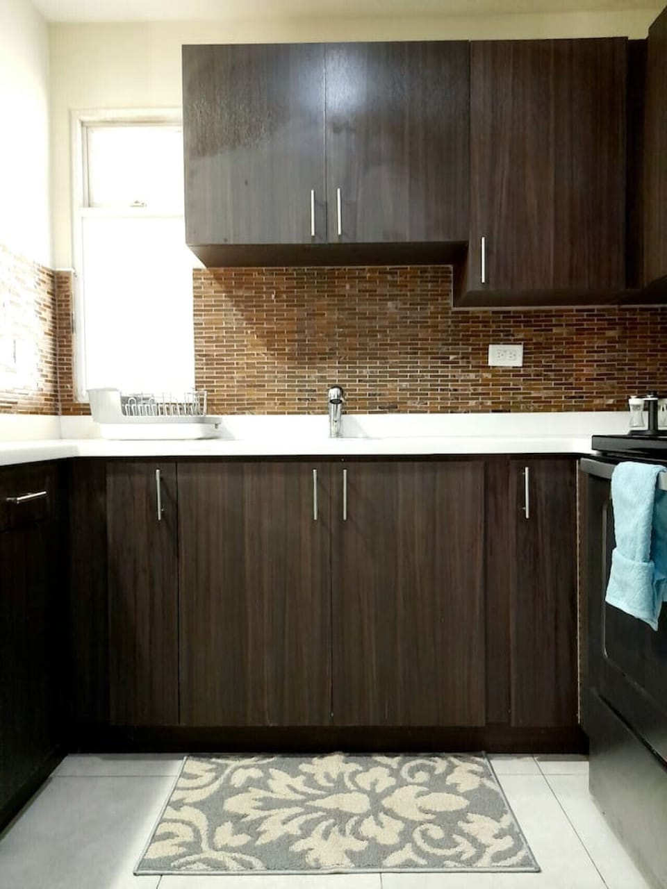 Kitchen counter w/ sink, sleek cabinetry & mosaic backsplash for a stylish cooking space
