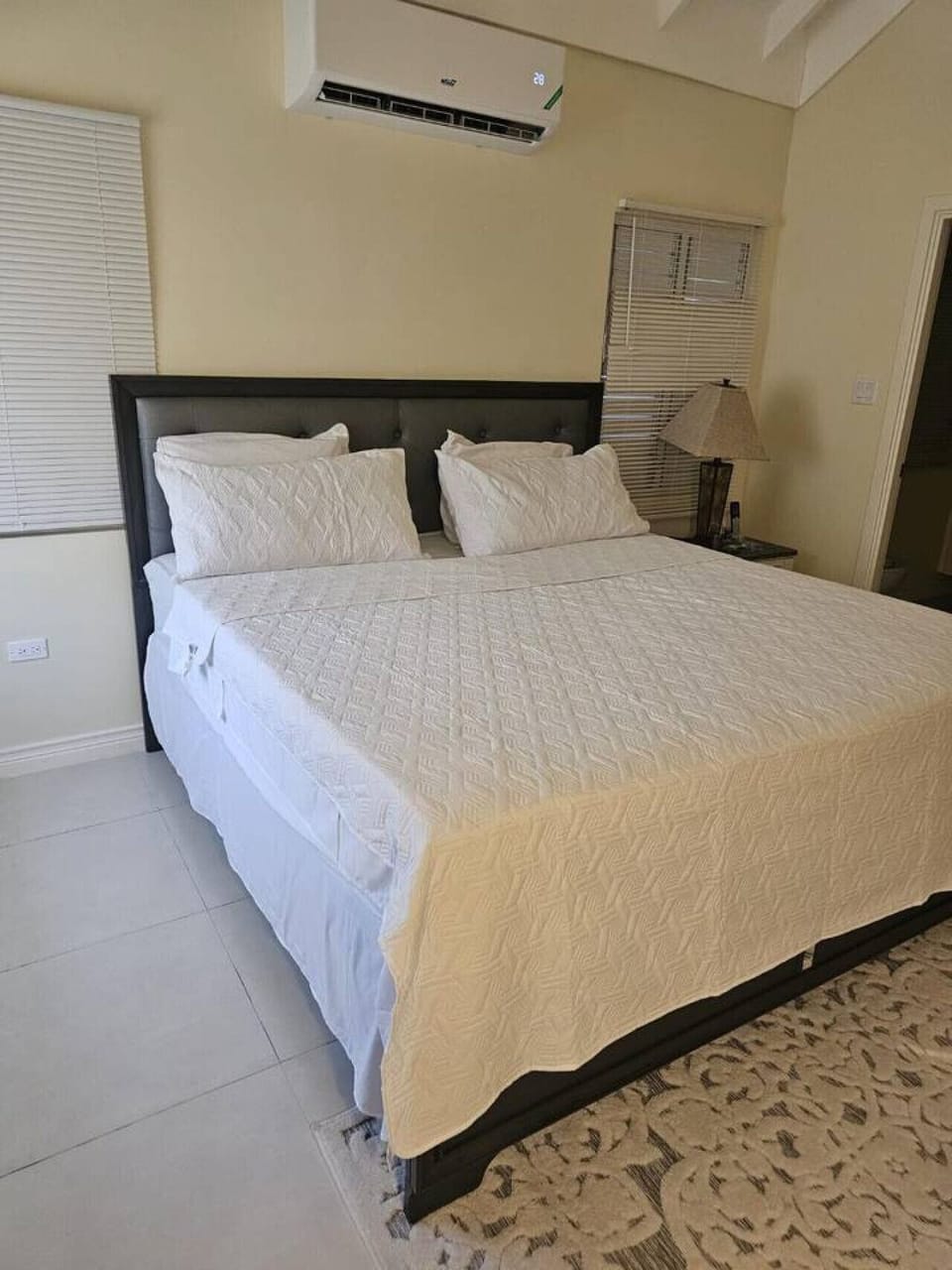 Comfortable bedroom w/ a neatly made bed and bedside lamp for a calm, cozy retreat.