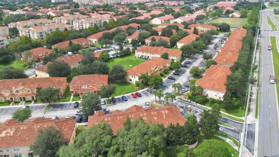 Aerial view of a residential community with terracotta roofs and ample parking.