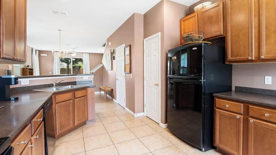 Spacious kitchen with modern black appliances and warm wood cabinetry.