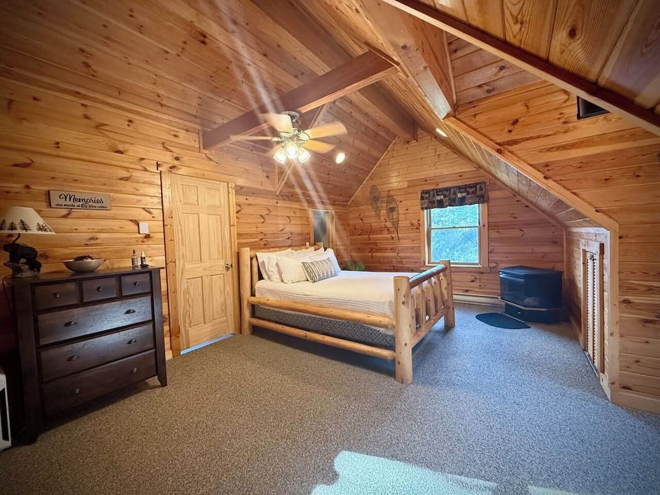 Cozy main bedroom featuring a warm fireplace, plush queen bed with lots of pillows, and a smart TV—perfect for breakfast in bed. 