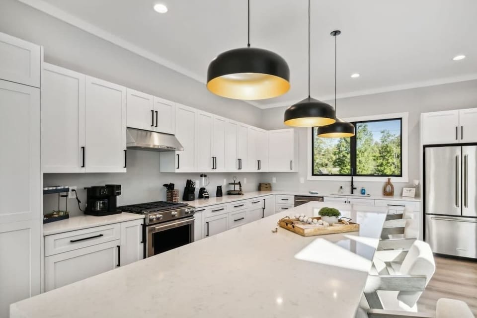 Luxurious kitchen with waterfall edge quartz countertops, Kitchen Aid appliances, gas stove, hidden pantry, dishwasher, hidden microwave, and wine cooler