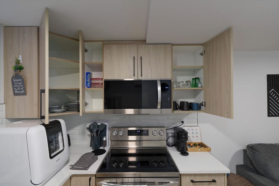 Fully stocked kitchen with dishes, glasses, cookware, and small appliances.
