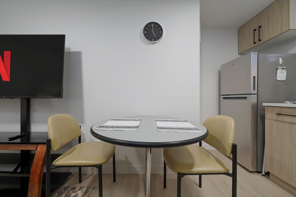 Simple dining area for two with placemats, fridge access, and TV in view.