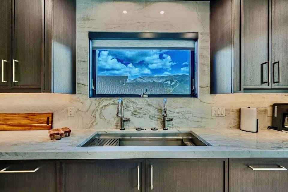 Enjoy stunning views while you cook in this modern kitchen, featuring sleek countertops, high-end fixtures, and a picture-perfect window that brings nature right to your workspace.