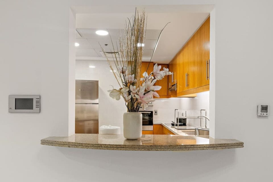 Kitchen pass-through counter with a vase of flowers, overlooking a modern kitchen.
