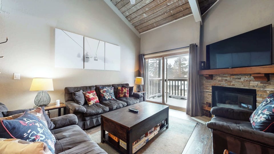 Open living space with fireplace, TV, and balcony