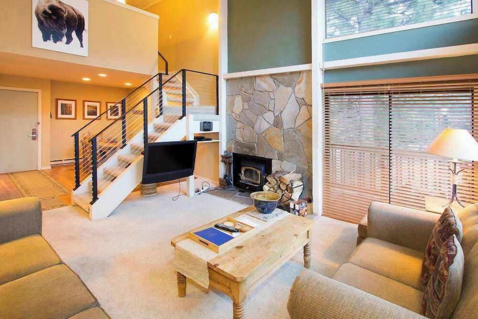 Living room w/ flat screen TV, DVD player, wood burning fireplace, balcony access