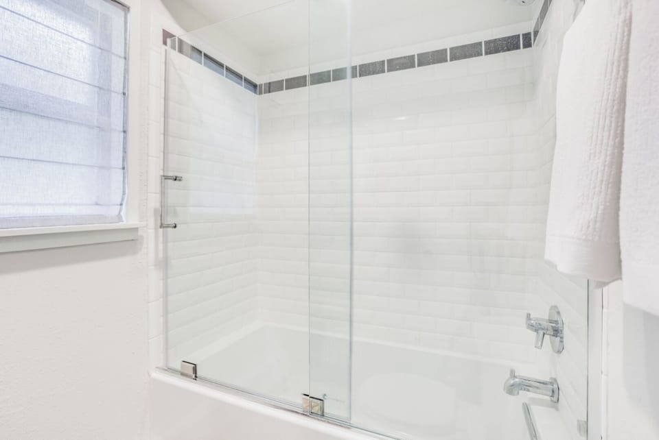 Slip into this pristine tub and let the day's stress melt away. The gleaming tile, glass enclosure, and fresh towels create your personal spa retreat.