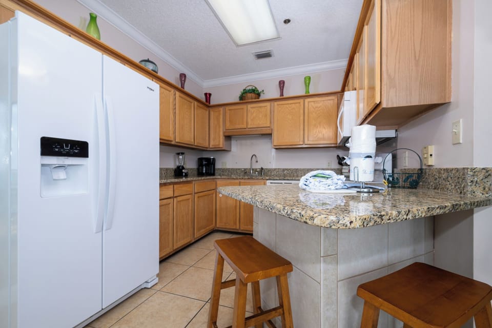 Prepare meals in the spacious kitchen featuring ample counter space, wooden cabinetry, and white appliances