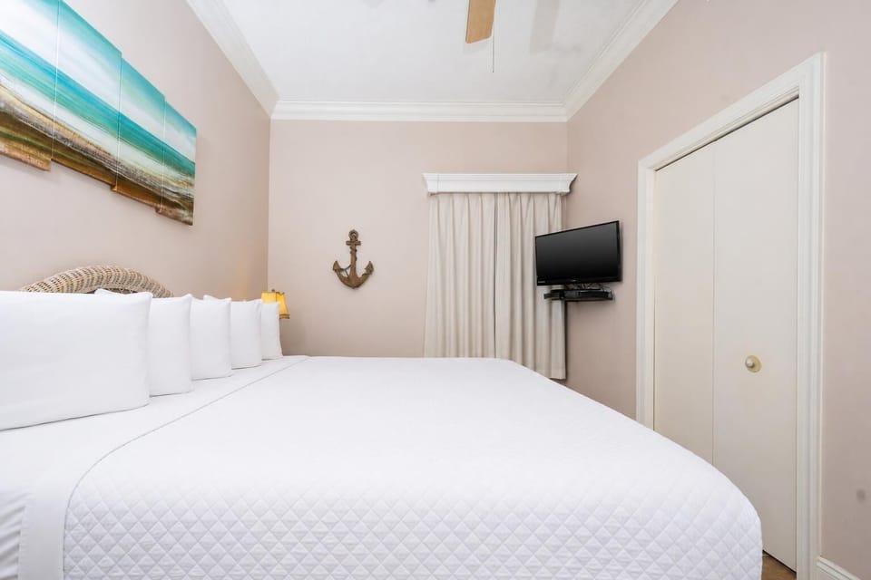Relax in the inviting bedroom featuring a large bed, coastal decor, and a TV needs