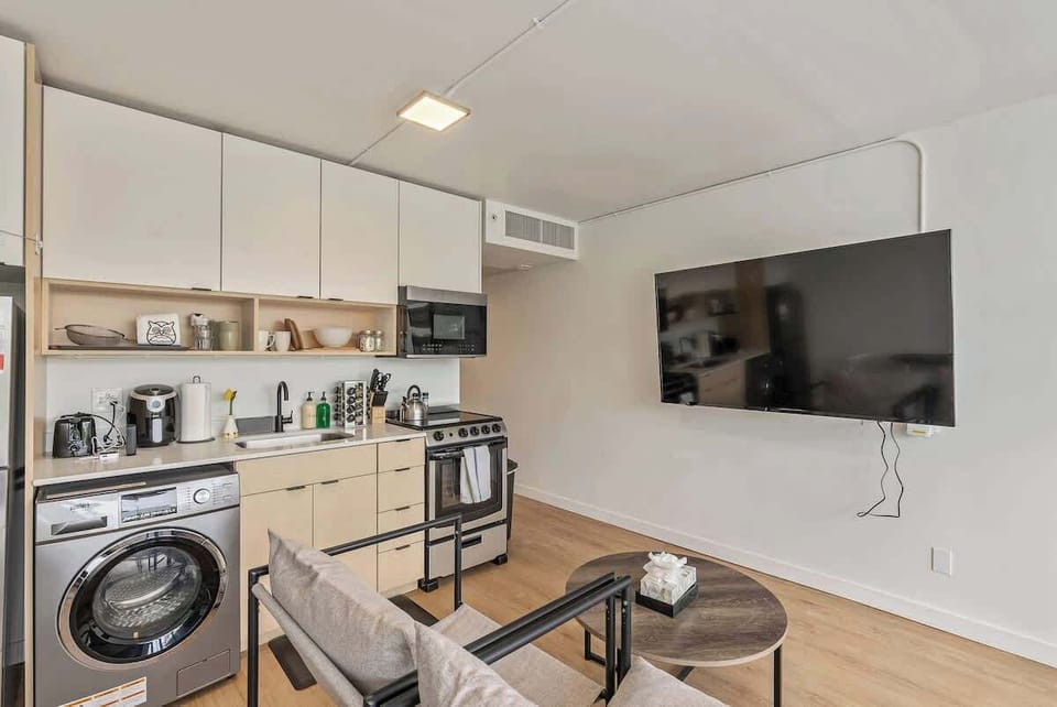 Comfortable living area w/ TV, small sofa & functional kitchen in an open layout