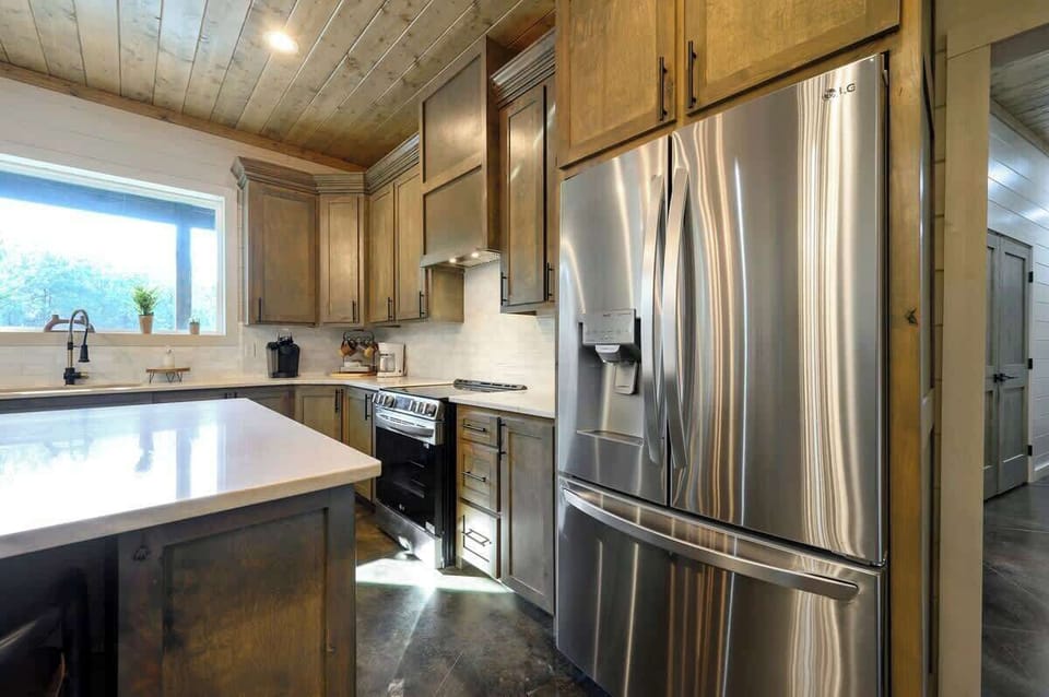 Gourmet kitchen with stainless steel LG appliances, wood cabinets, and elegant quartz countertops.

