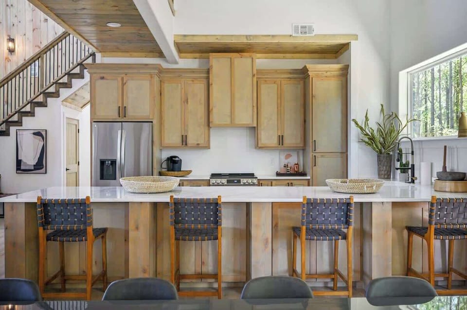 Spacious modern kitchen with wood cabinets, quartz countertops, and stylish bar stools—perfect for entertaining.