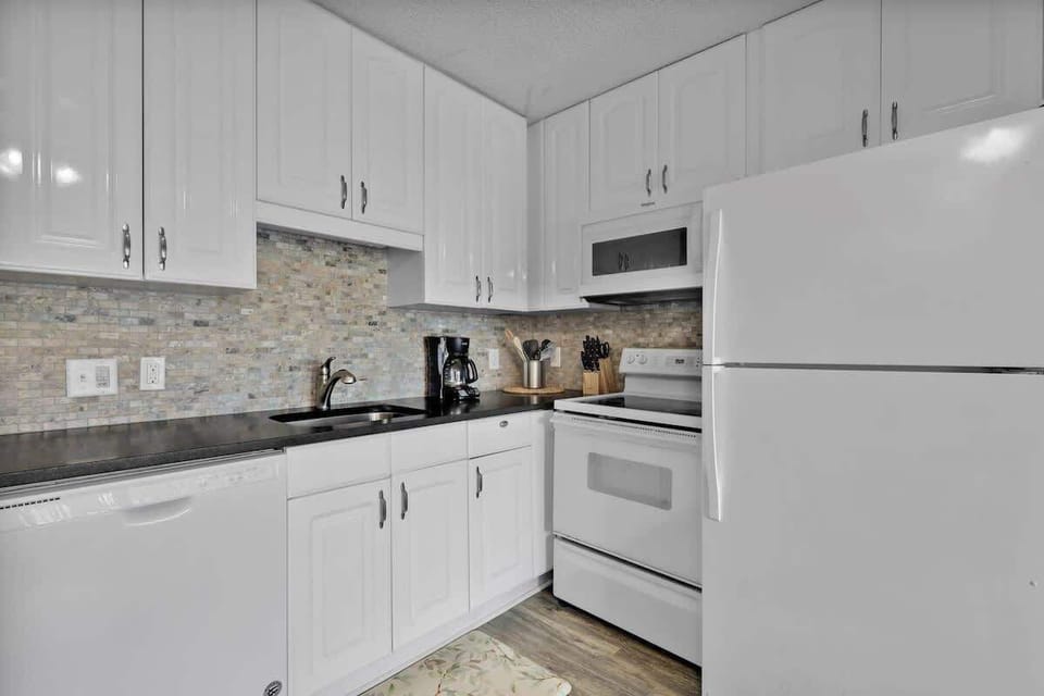 All-white kitchen equipped with full-sized appliances, making in-home dining easy.