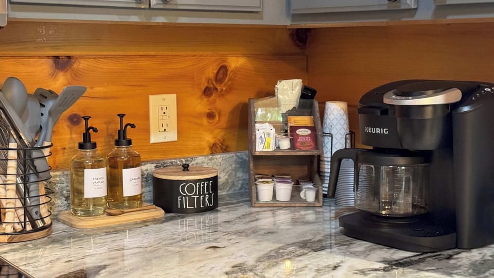 coffee station with a keurig machine, flavored syrups, and a variety of coffee pods on a marble countertop